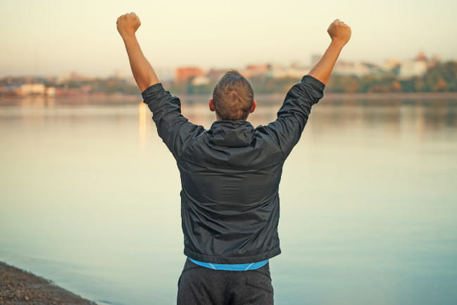 A person is seen from behind lifting their arms into the air.
